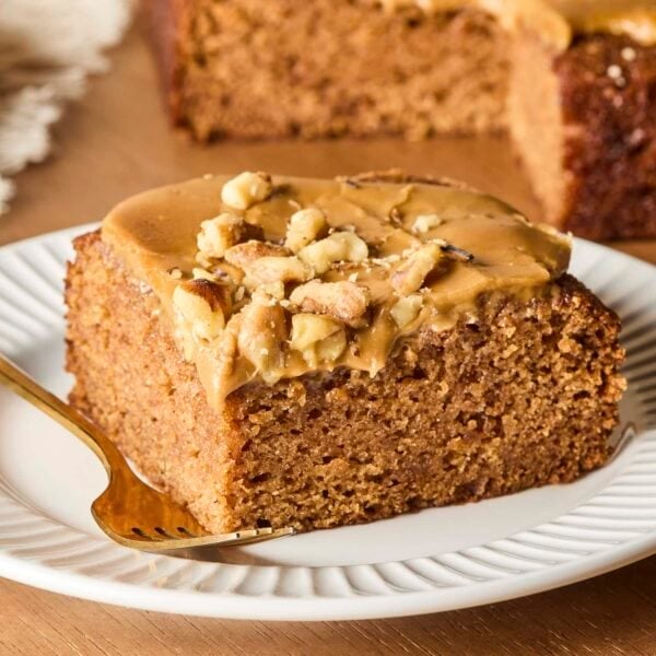 Applesauce cake with caramel frosting after being sliced from the rest of the cake.