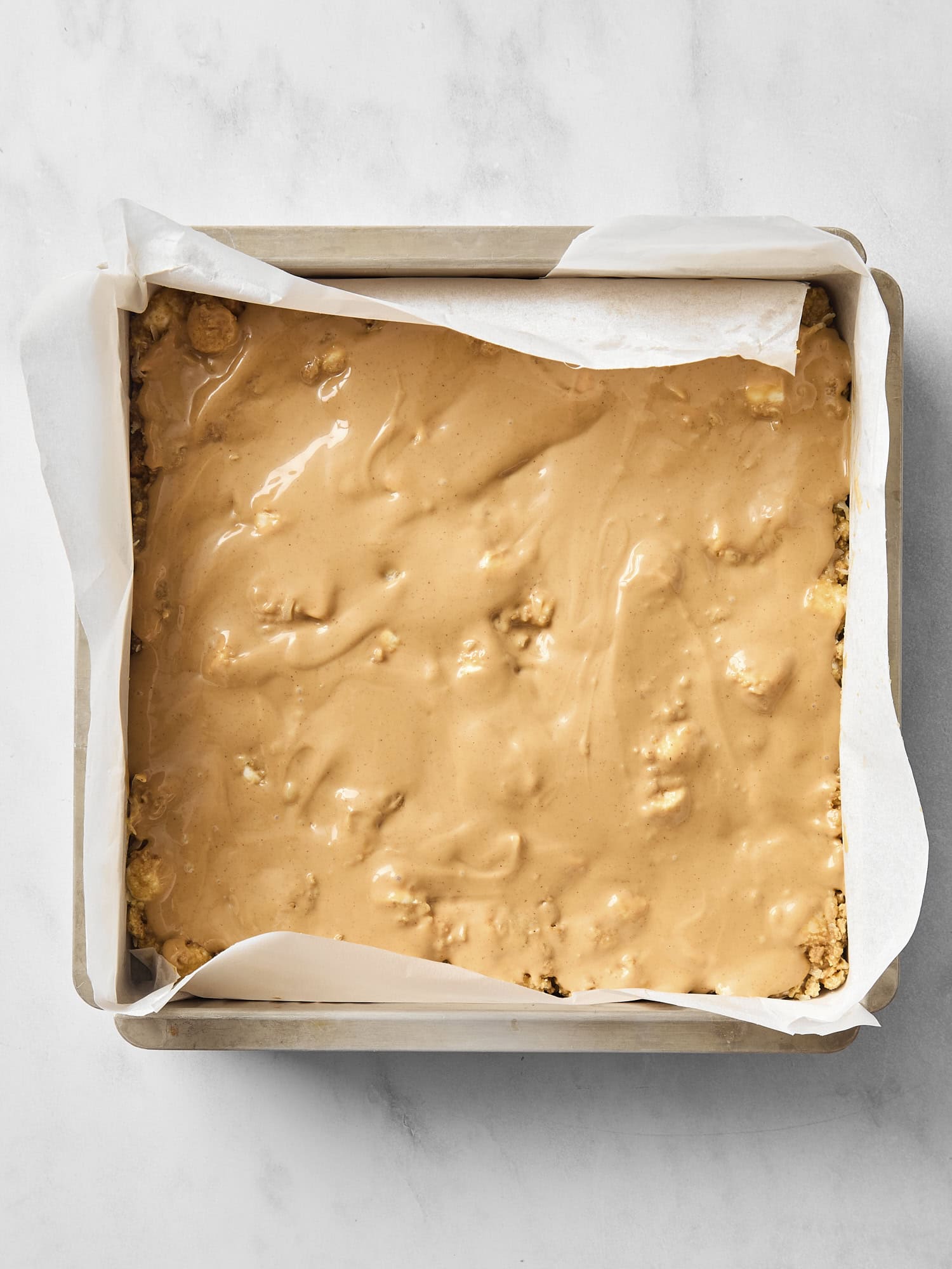 Butterscotch bars in a baking pan with a melted butterscotch and peanut butter layer on top.