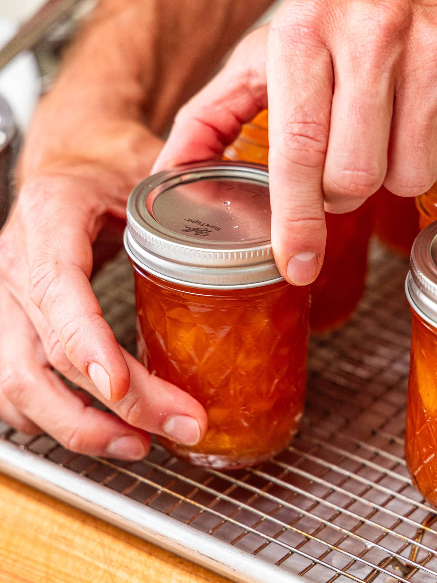 Tightening rings to jars with peach jam.