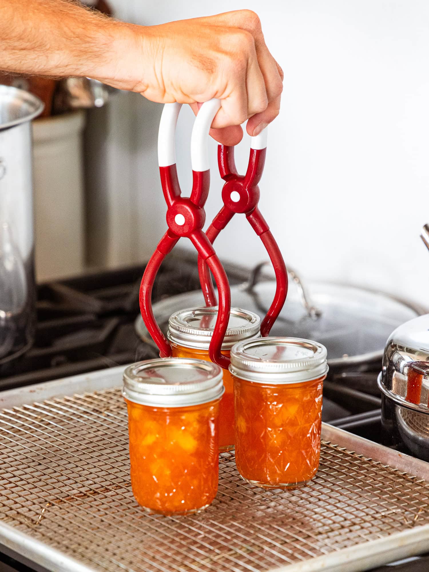 Removing the jars of peach jam from the water bath.