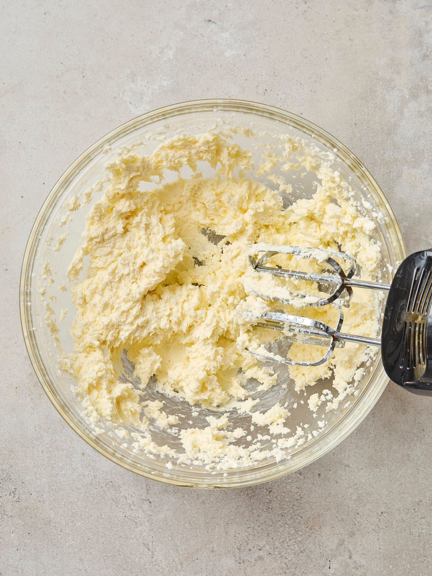 Glass bowl filled with mixture of butter and sugar after being mixed together.