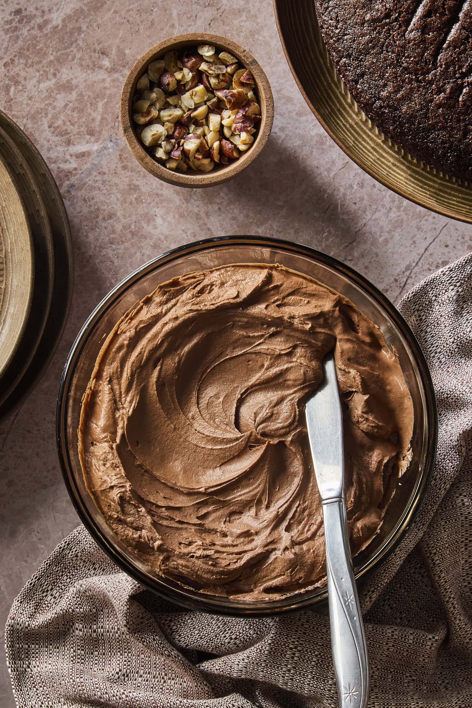 Brown colored chocolate frosting with creamy texture in a glass bowl.