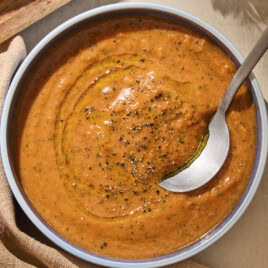 Bowl of gazpacho soup with black pepper sprinkled on top and spoon scooping a serving.