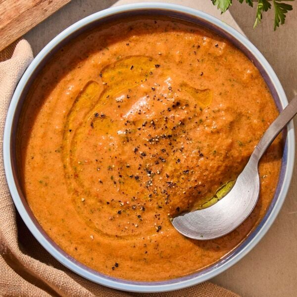 Blue bowl with creamy gazpacho soup inside with spoon.