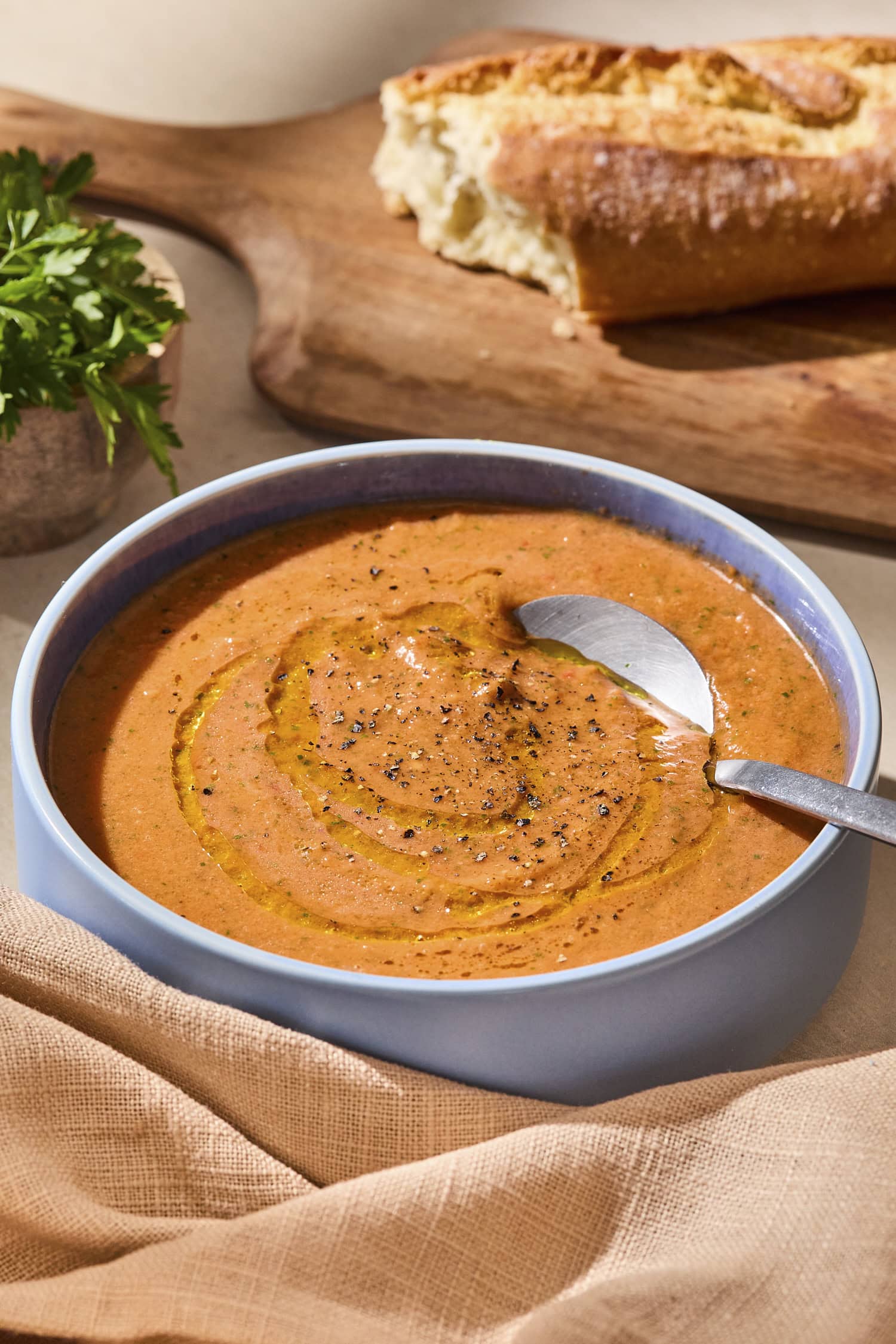 Blue bowl filled with creamy gazpacho soup with a spoon scooping out a serving.