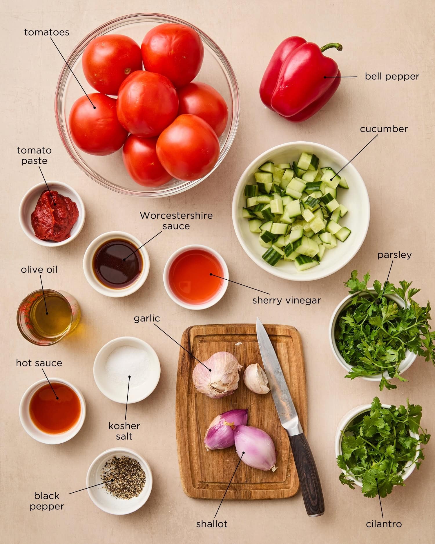 Surface filled with ingredients for gazpacho soup including tomatoes, cucumbers, and more.
