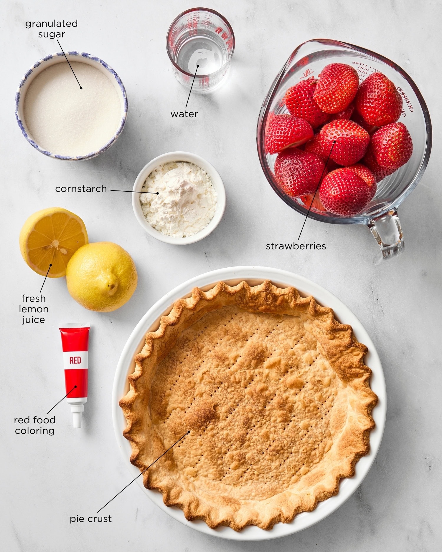 White marble surface with ingredients needed for a strawberry pie.