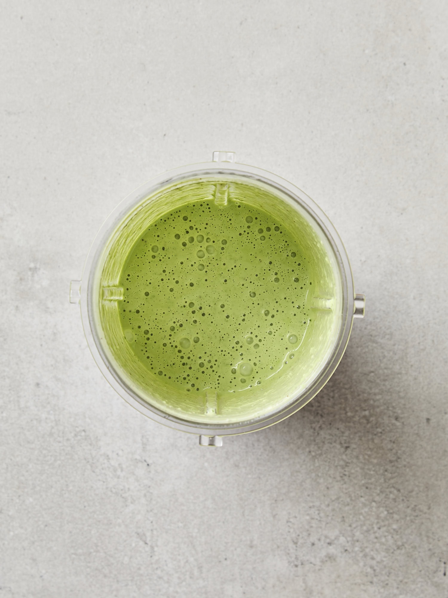 Blender container with blended green salad dressing.