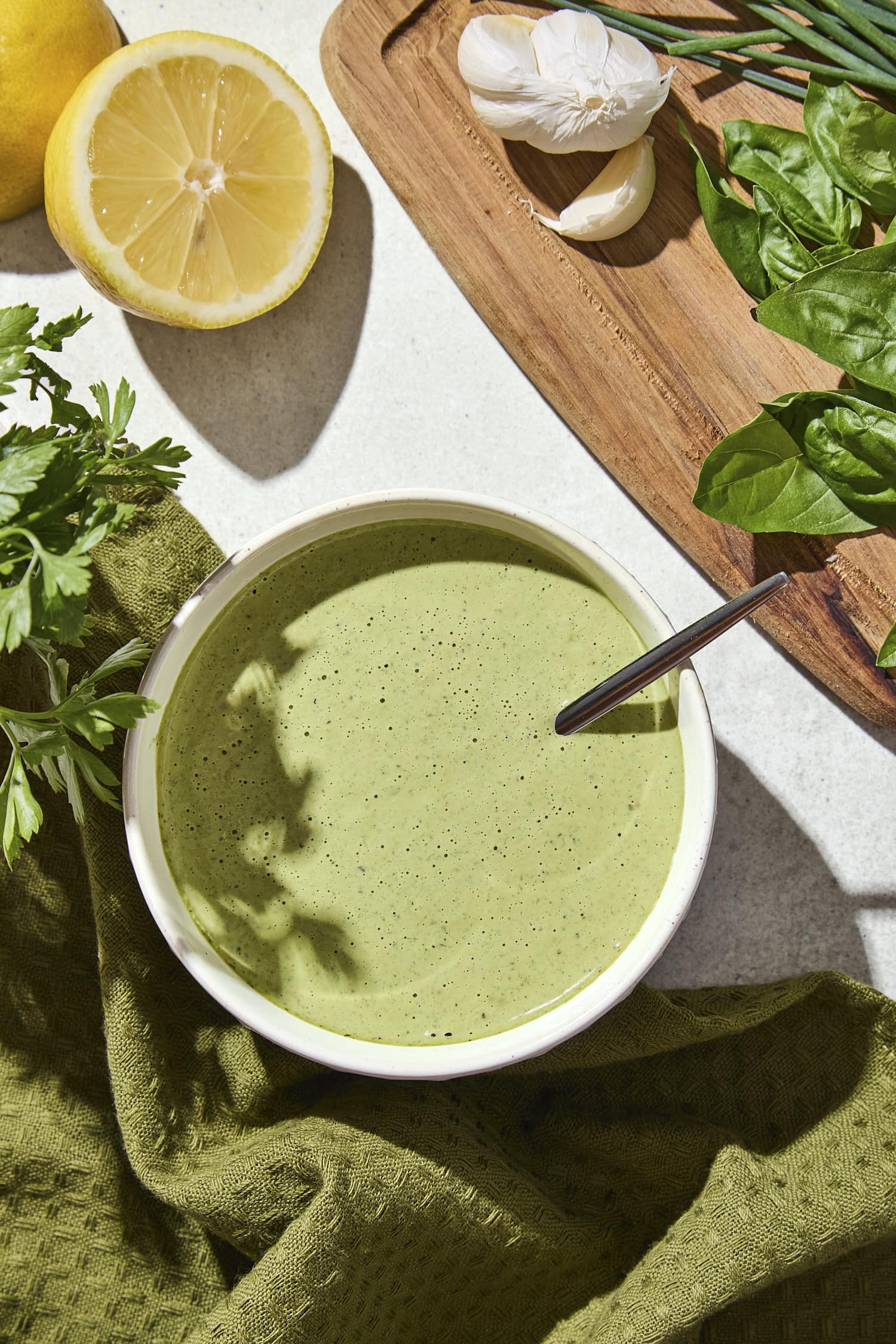 White bowl filled with green goddess dressing with lemon and herbs.