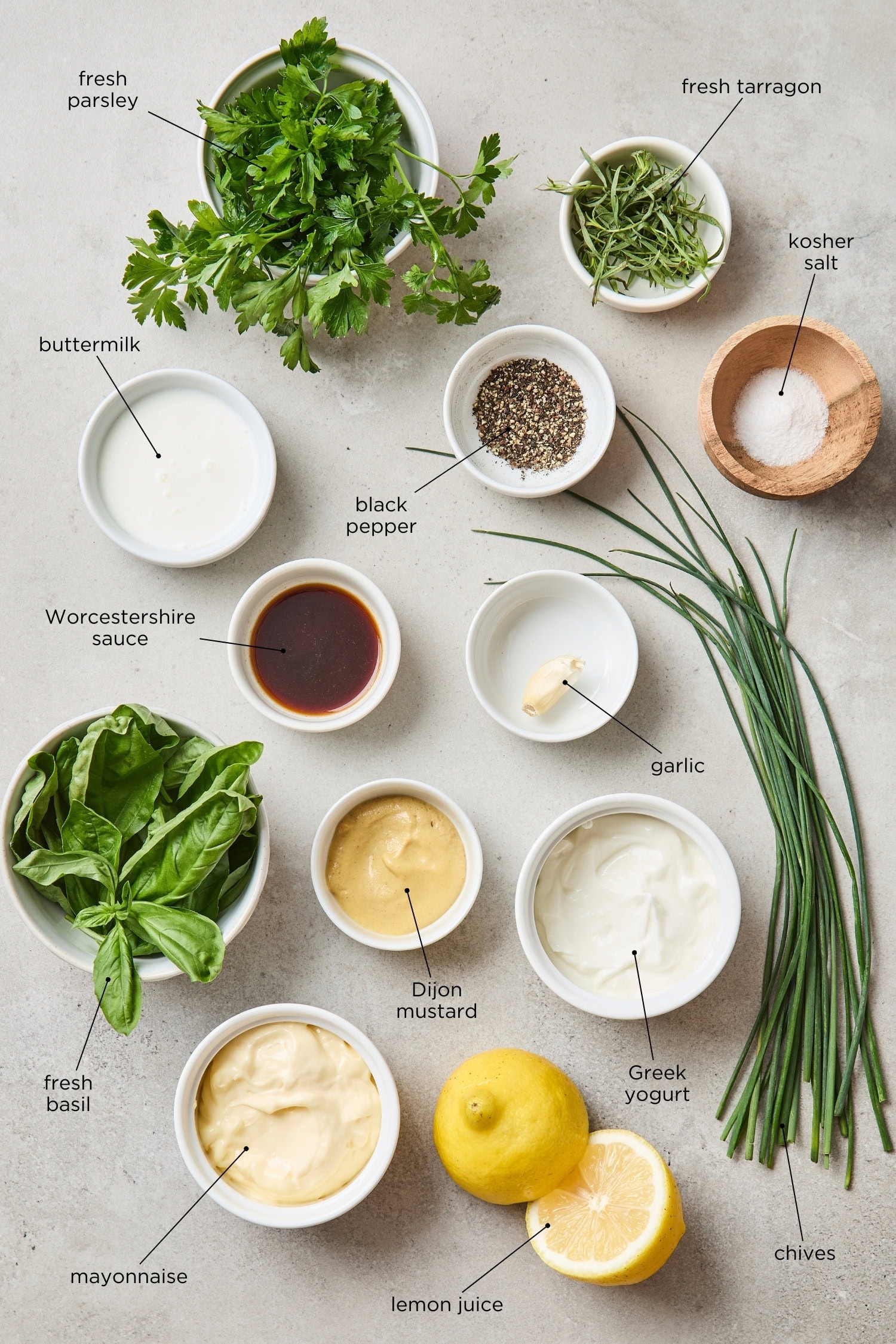 Surface filled with ingredients for a green goddess dressing including herbs, mayo, and more.