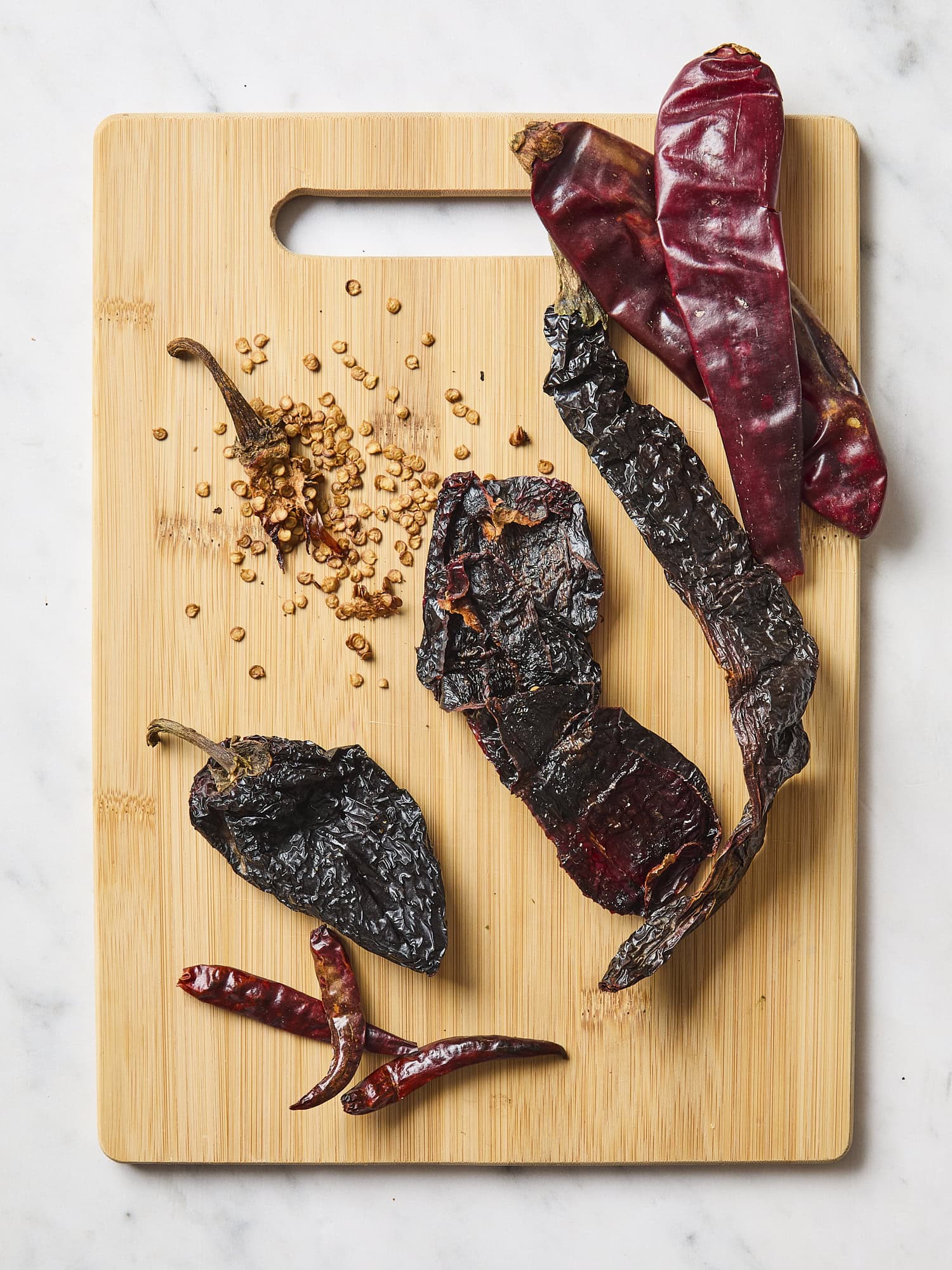 Cutting board with dried chiles with seeds removed.