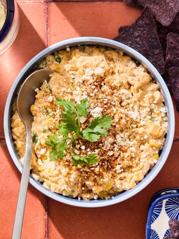 Bowl filled with street corn dip with Cotija cheese and cilantro sprinkled on top.