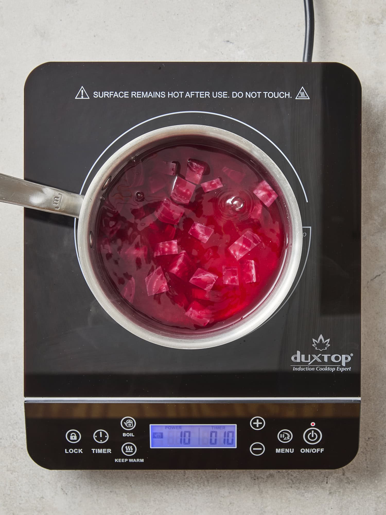 Beet brine cooking on a hot plate with deep red color.