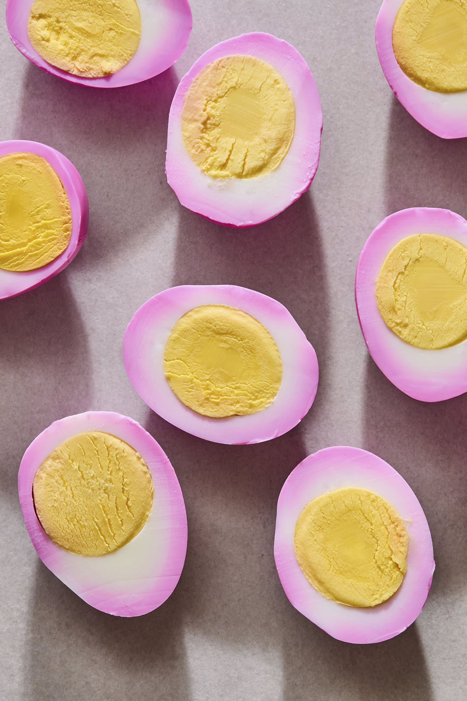 Red beet eggs sliced in half showing interior yellow yolk.