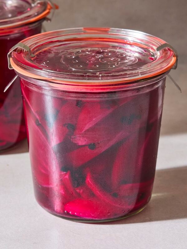 Jar of quick pickled beets with onions and peppercorns in red brine.