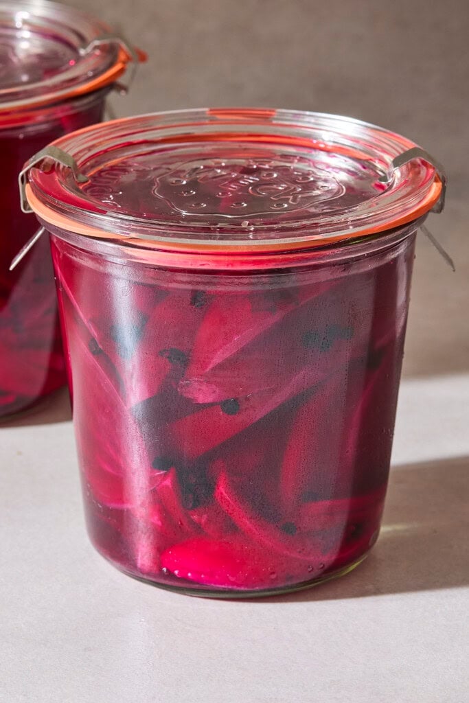 Jar of quick pickled beets with onions and peppercorns in red brine.
