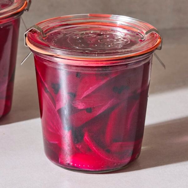 Jar filled with red colored pickled beets packed in brine.
