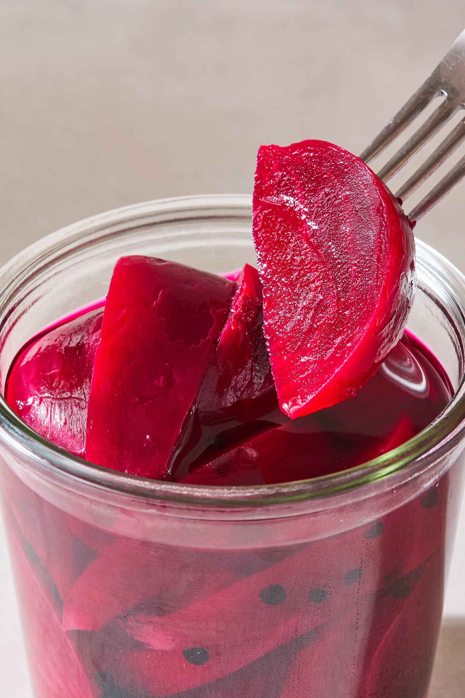 Pulling a pickled beet out of a jar with a fork.