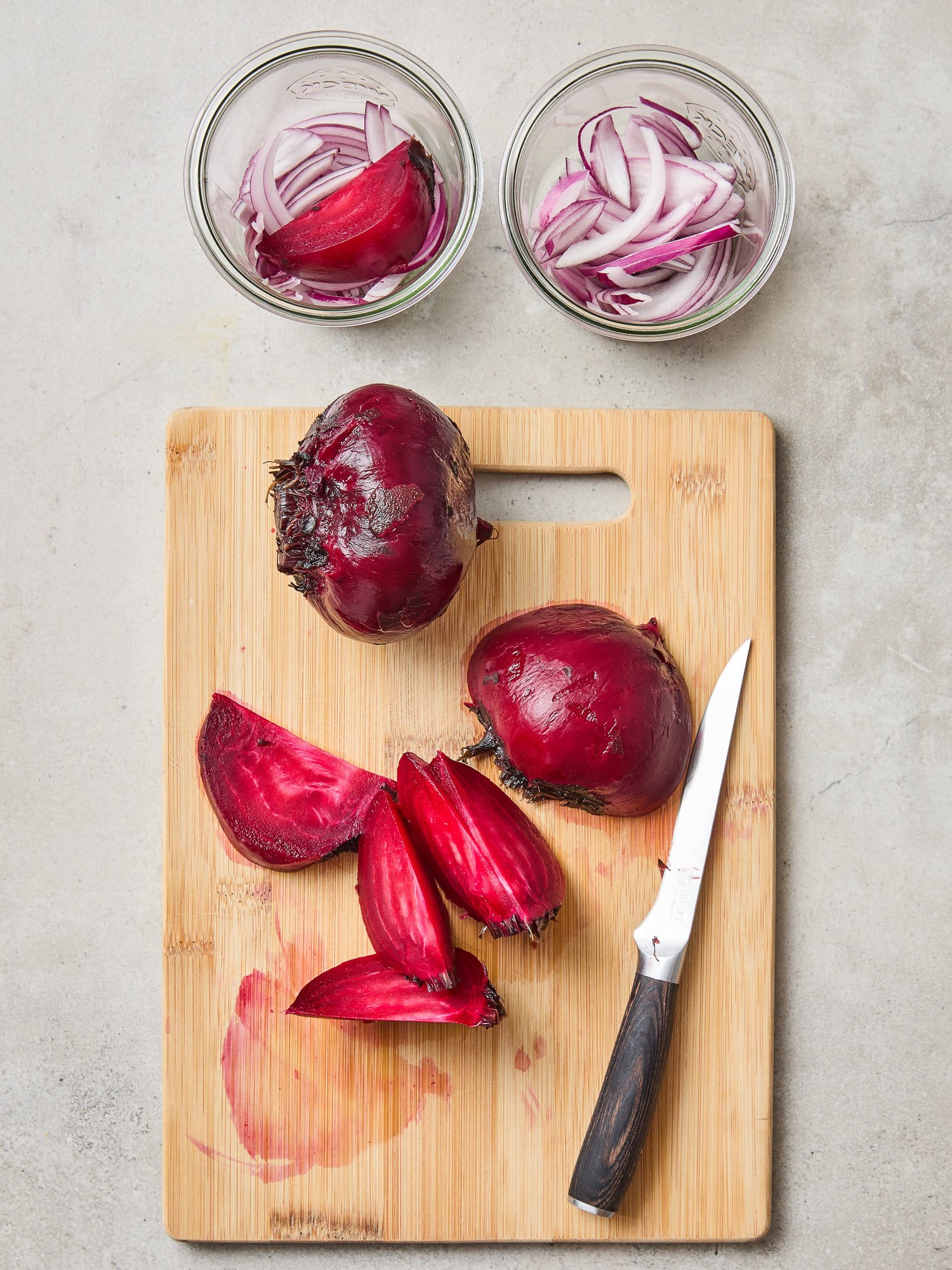 Wedging beets on a cutting board before adding them to a jar with red onion.