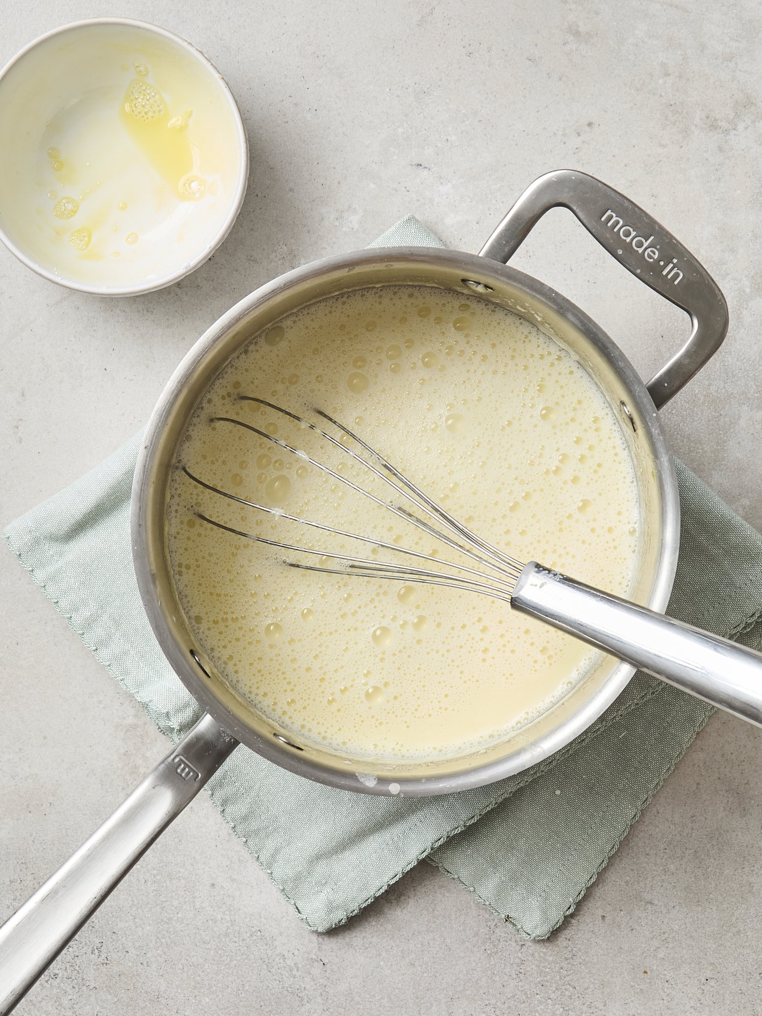 Saucepan with milk base for ice cream after cornstarch slurry is whisked in.