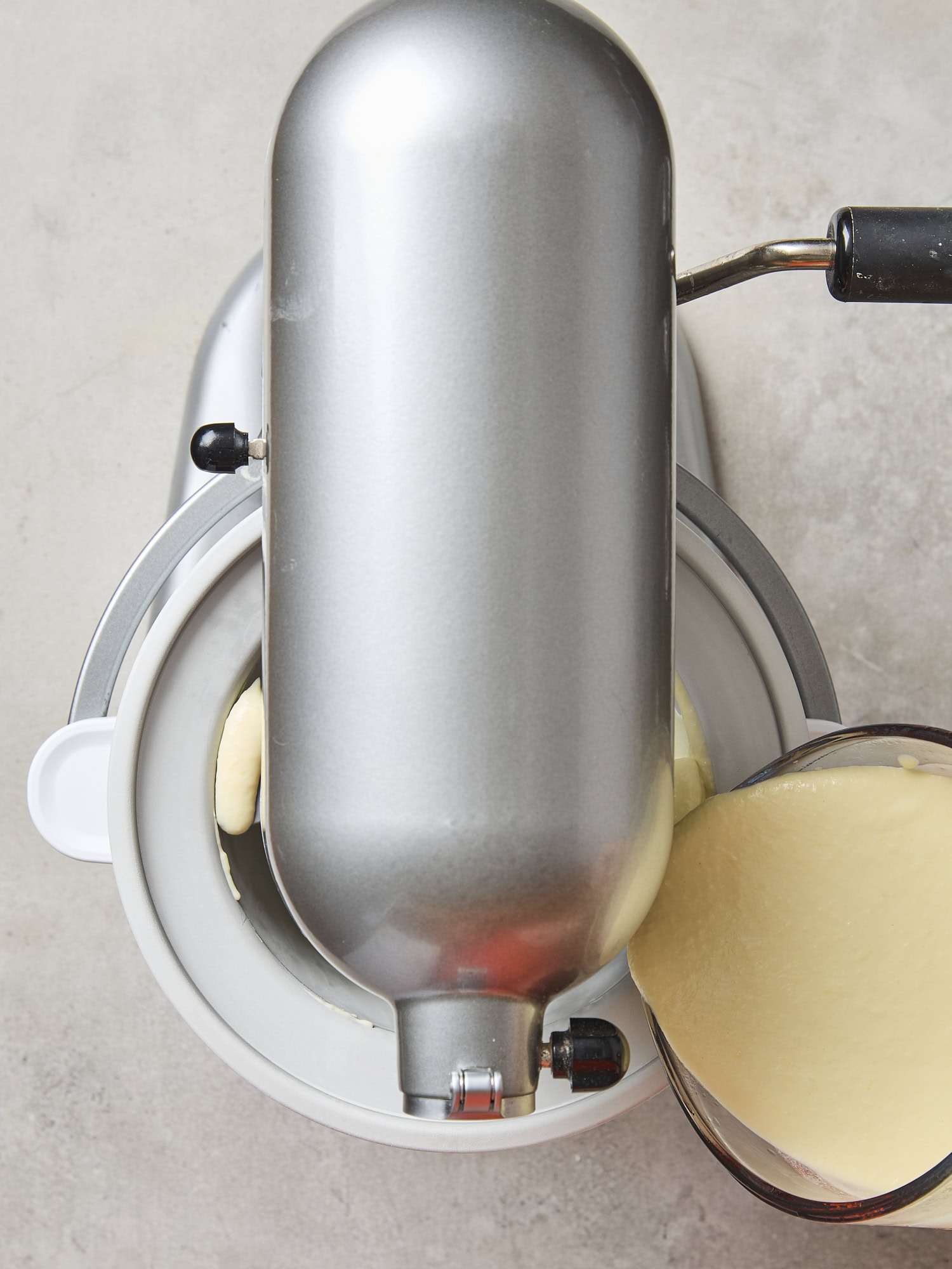 Stand mixer ice cream maker with sweet corn ice cream being poured into container.