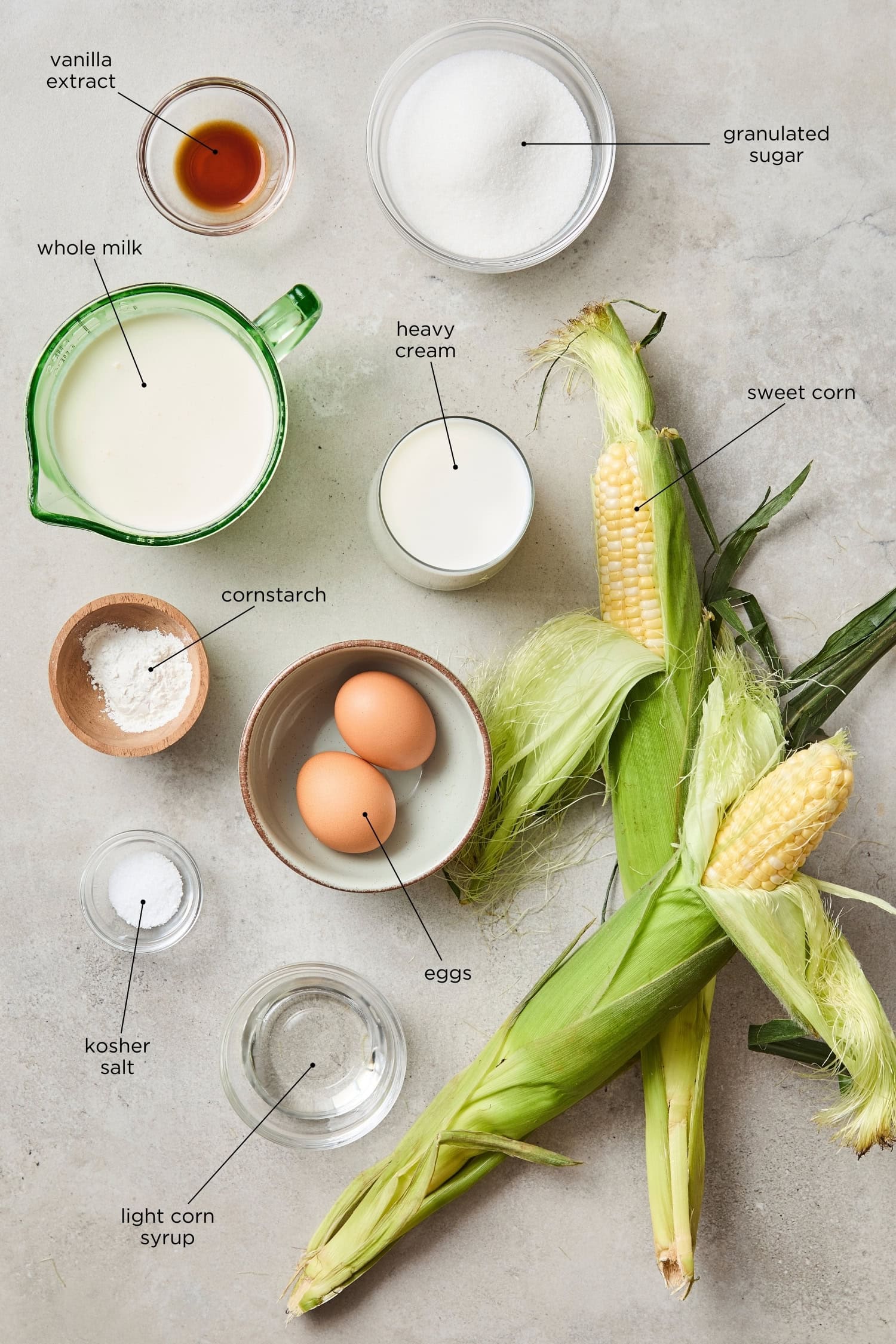 Concrete surface with ingredients needed for sweet corn ice cream including milk, cream, sugar, and more.