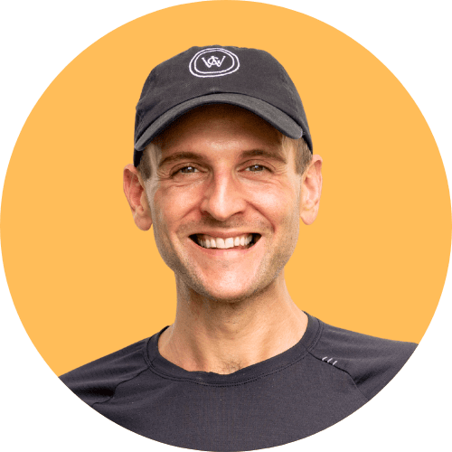 Kaleb Wyse standing in front of an orange background with a black hat.