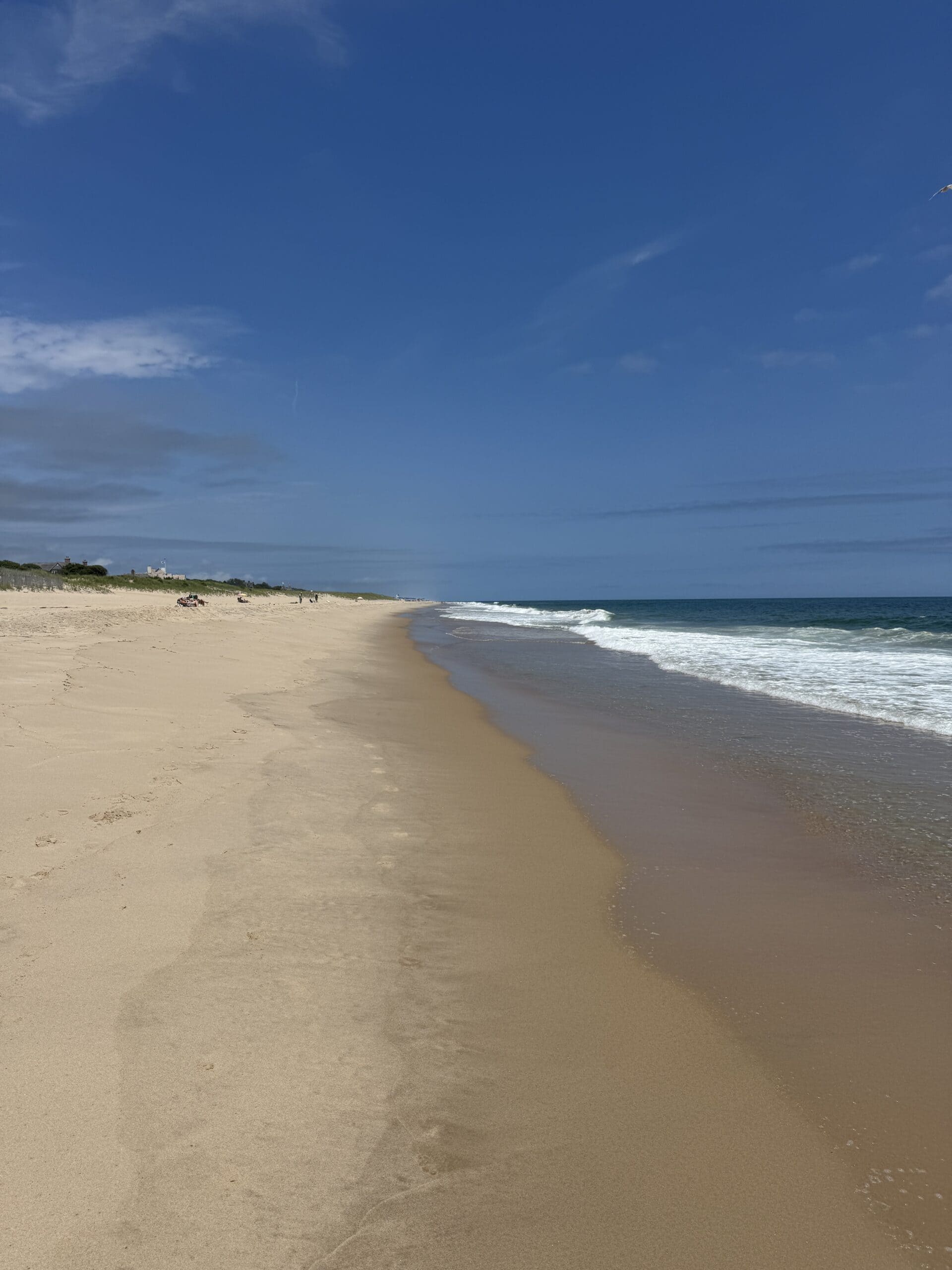 A beach with waves crashing with a bright blue sky.