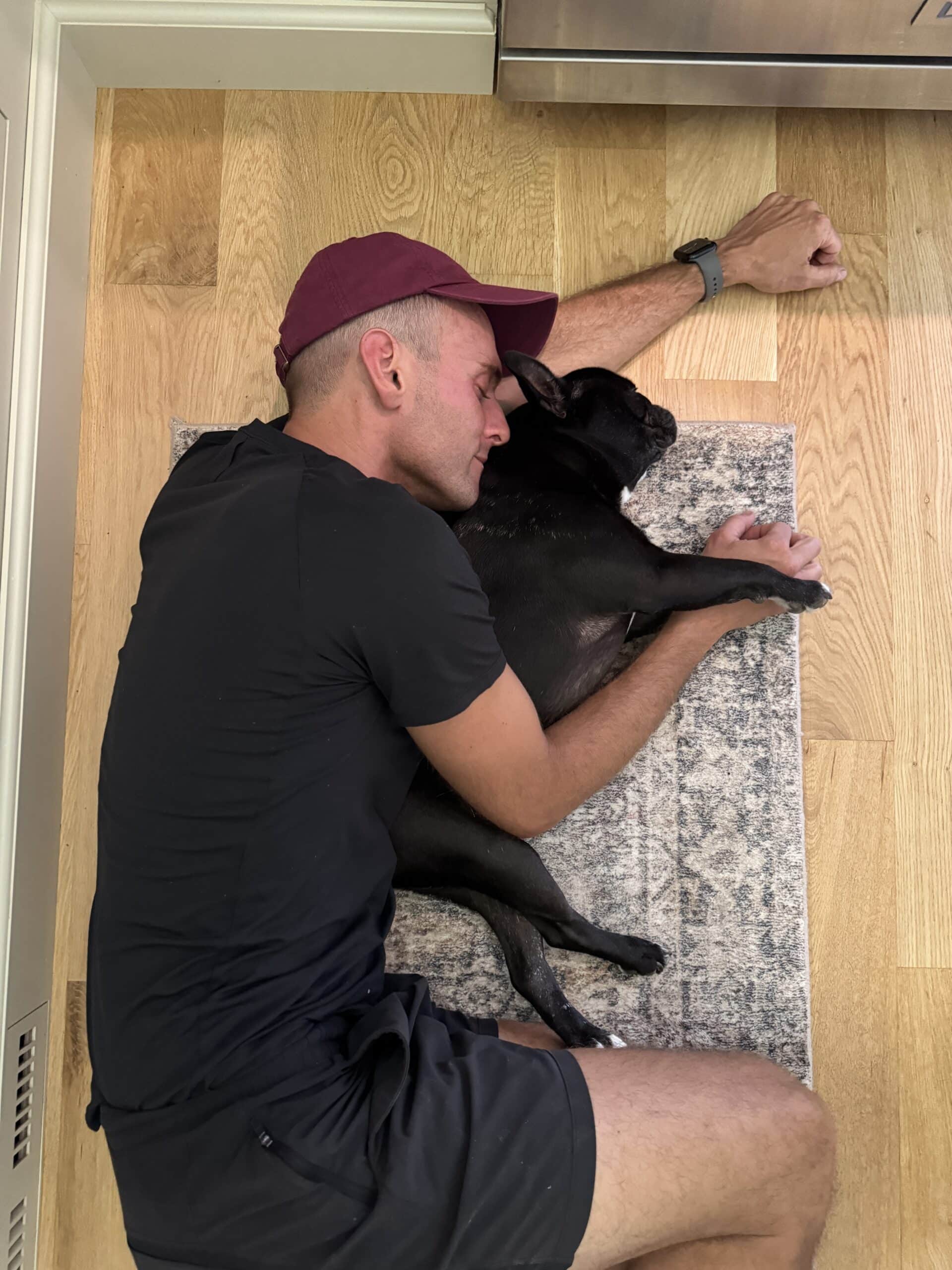 Kaleb Wyse laying on the floor hugging his French bulldog.