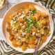 White serving bowl with tomato salad made with Sungold tomatoes and feta on top.