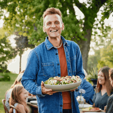 Kaleb Wyse standing with a salad in front of family.