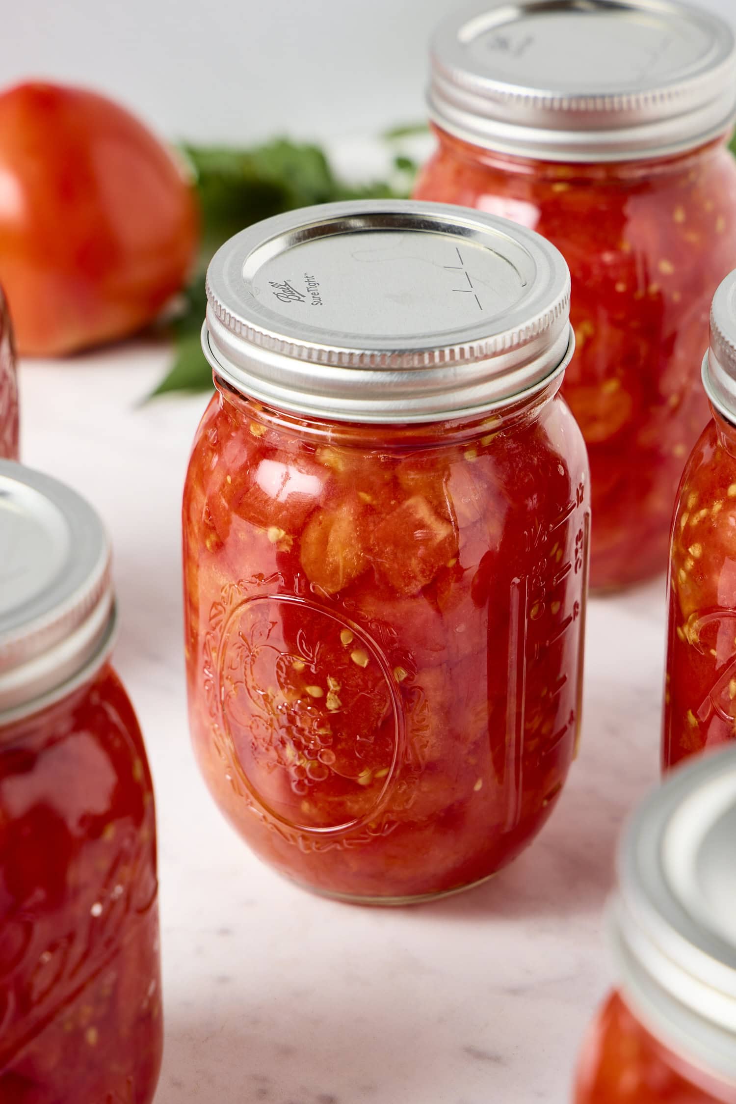 A glass jar filled with diced tomatoes.