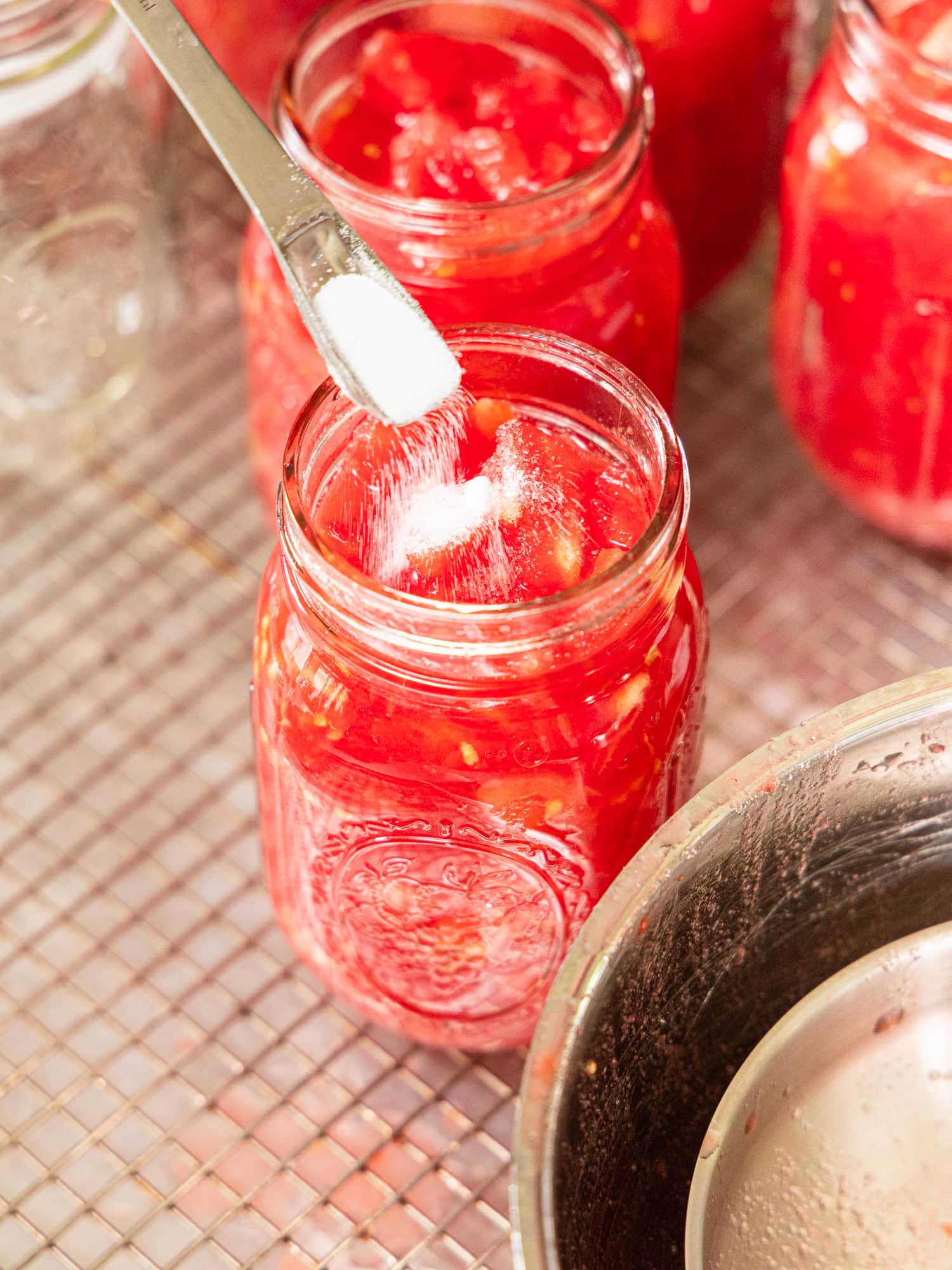 Adding salt to a jar of diced tomatoes.