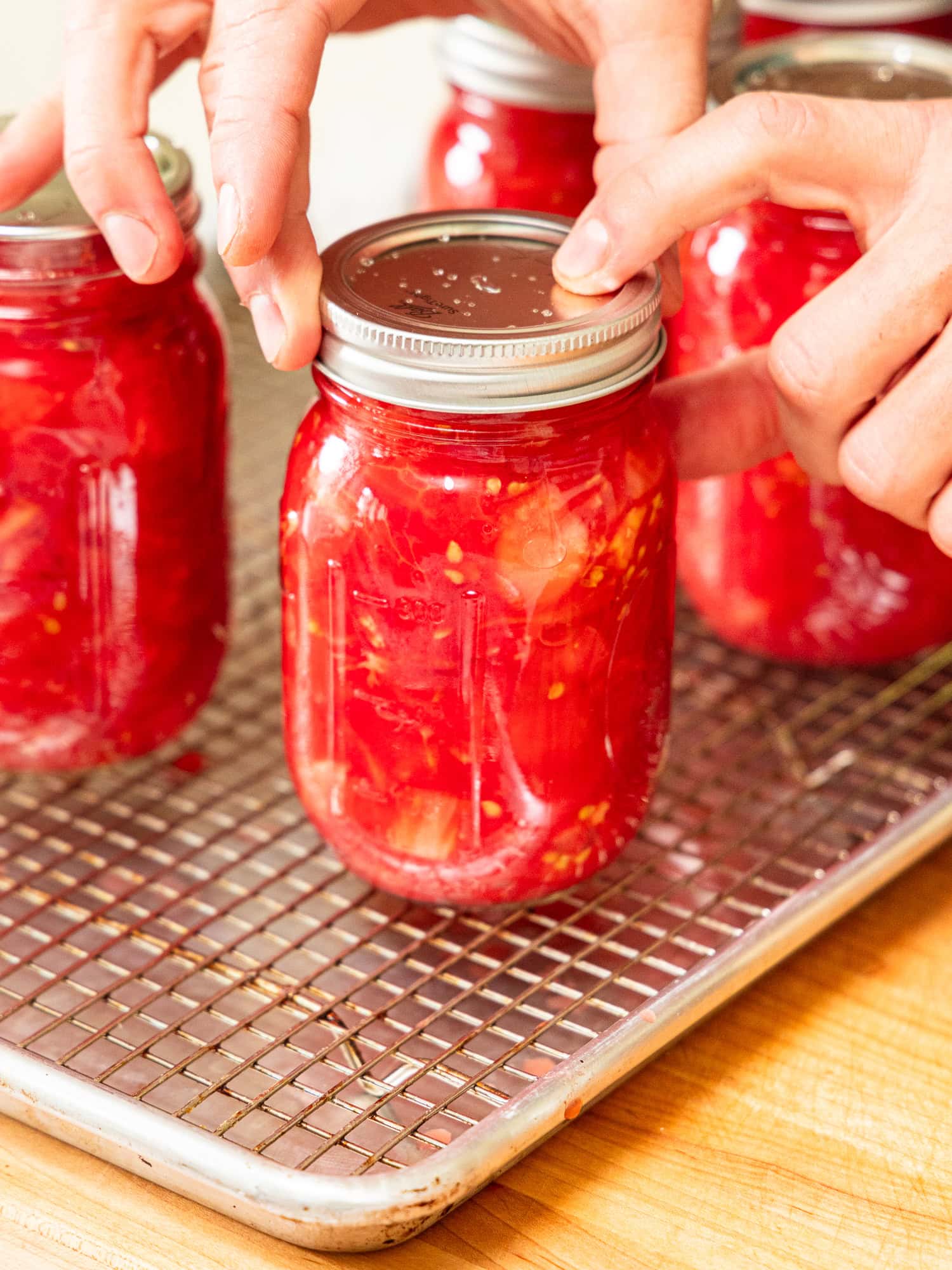Tightening the lid on a jar of diced tomatoes.