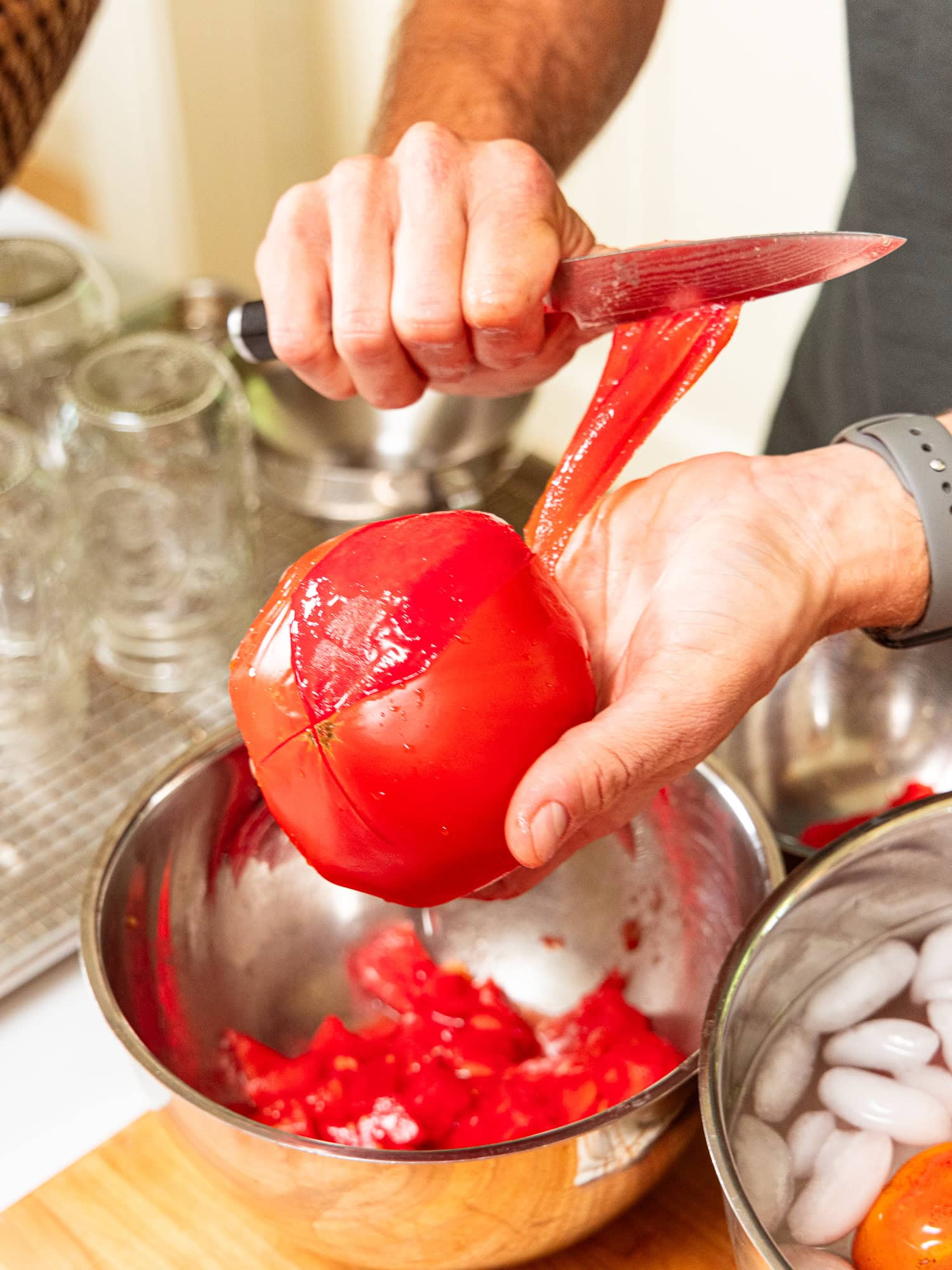 Peeling the skin off tomatoes after blanching them.
