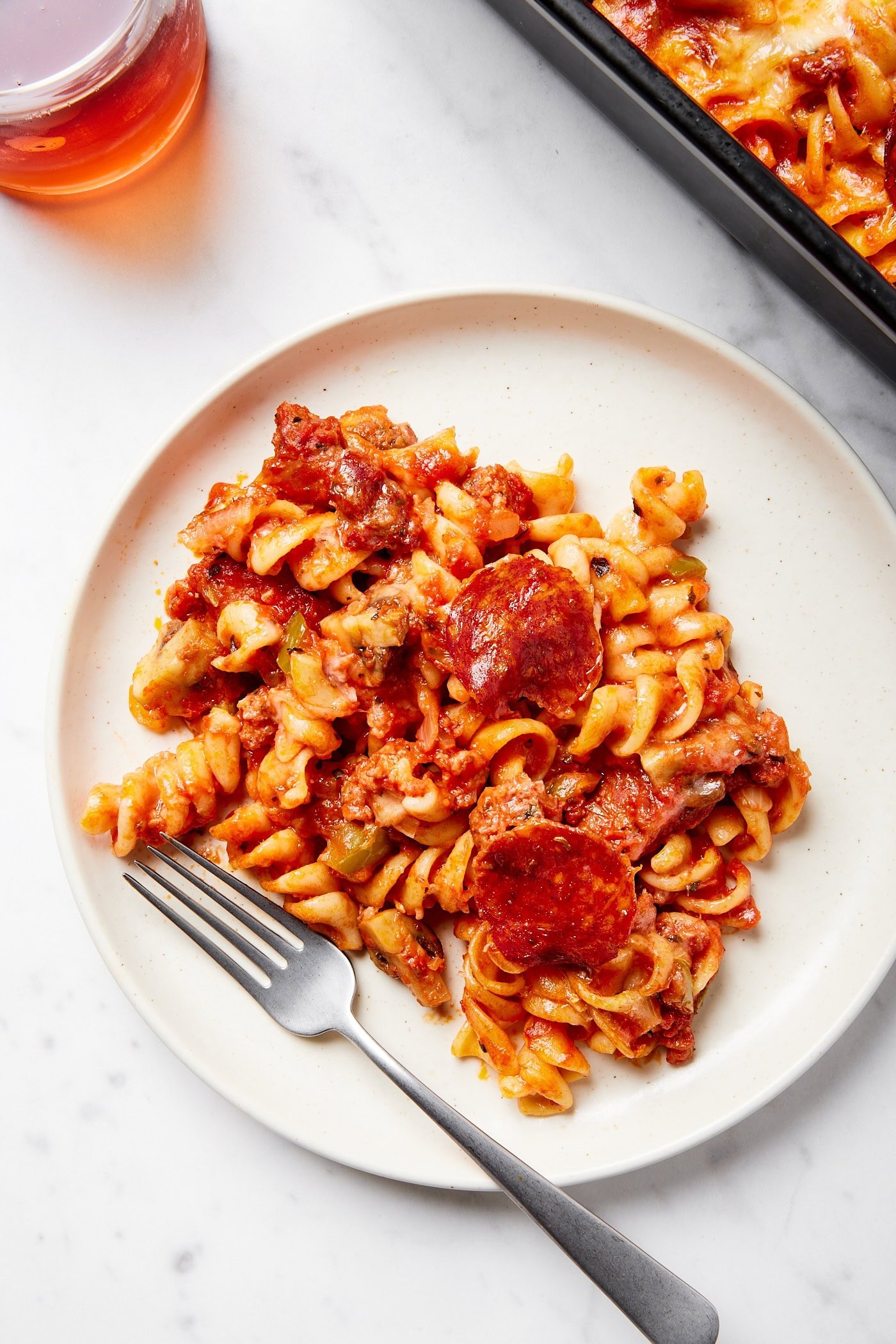 White plate with a serving of pizza casserole with fork on plate.