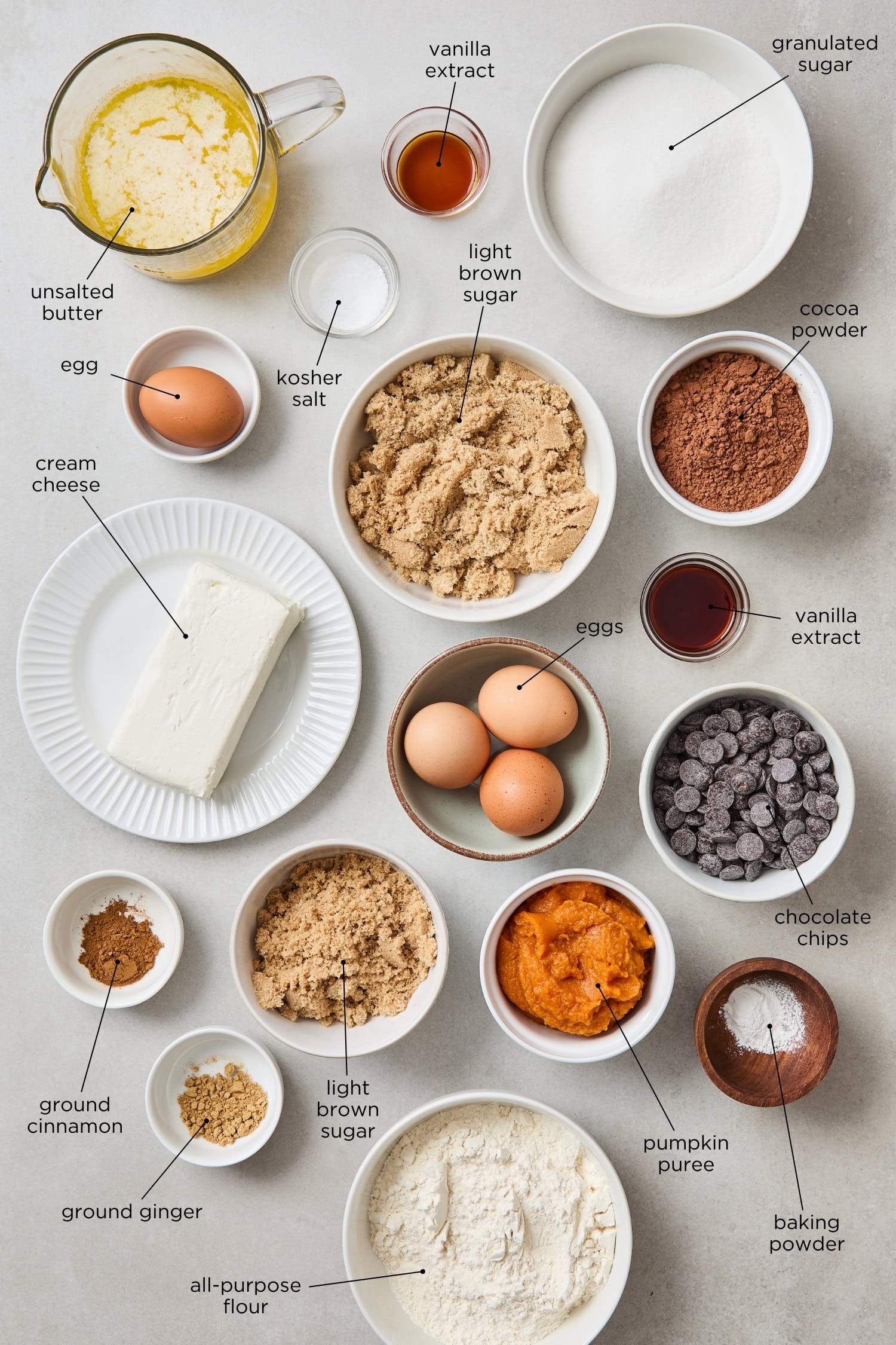 Concrete surface with ingredients to make brownies with pumpkin cheesecake swirl.