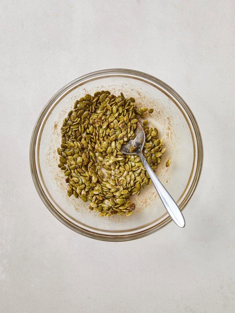 Pepitas coated in a spice mixture in a small bowl.
