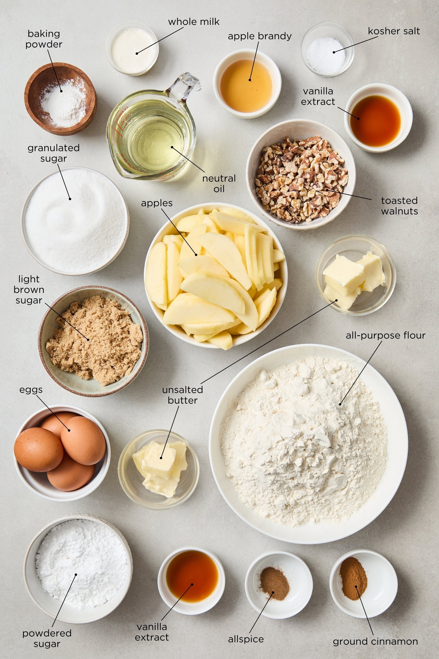 Surface filled with ingredients for a spiced apple cake including apples, sugar, flour, and more.