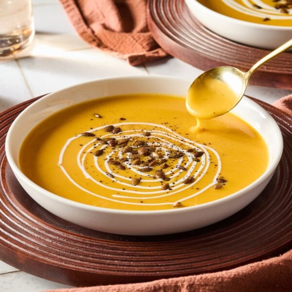 White bowl filled with squash soup with spoon pulling up a serving.