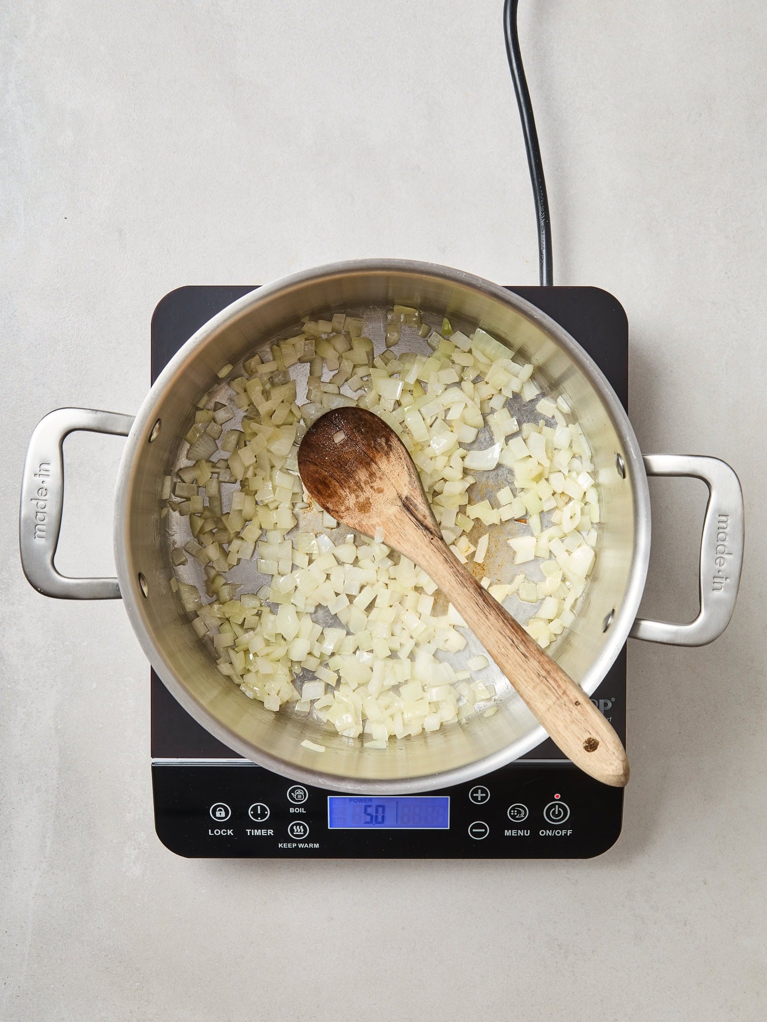 Onions saute in a pot on a stove.