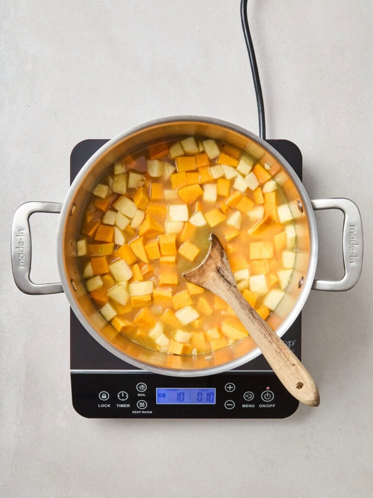 Squash and apple pieces begin to cook down over heat.