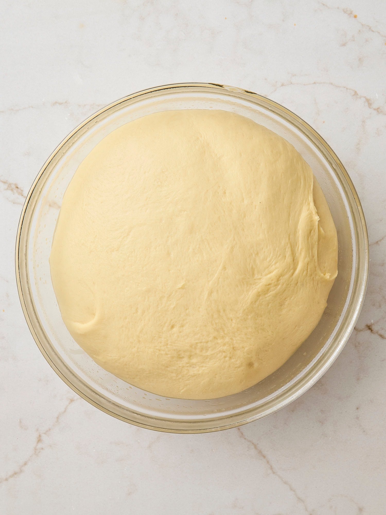 Glass bowl with risen dough for cinnamon rolls.