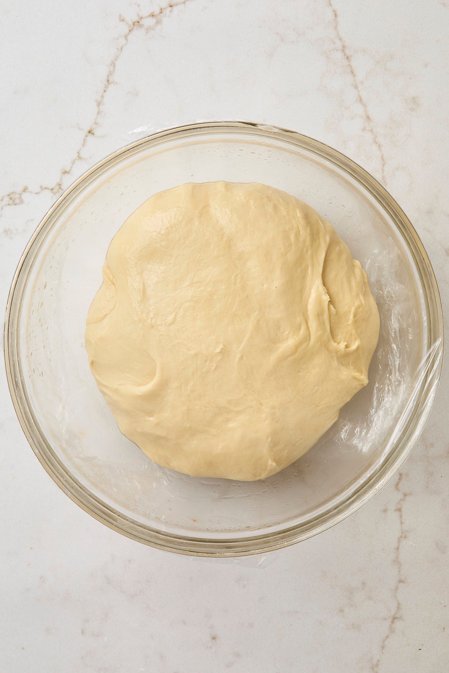 Glass bowl with dough after being kneaded with butter.