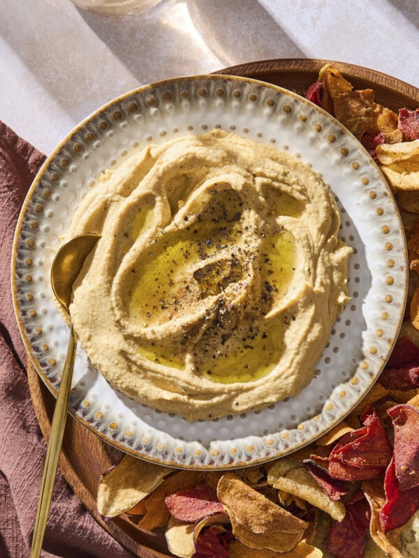A plate with butternut squash hummus topped with black pepper and a drizzle of olive oil.