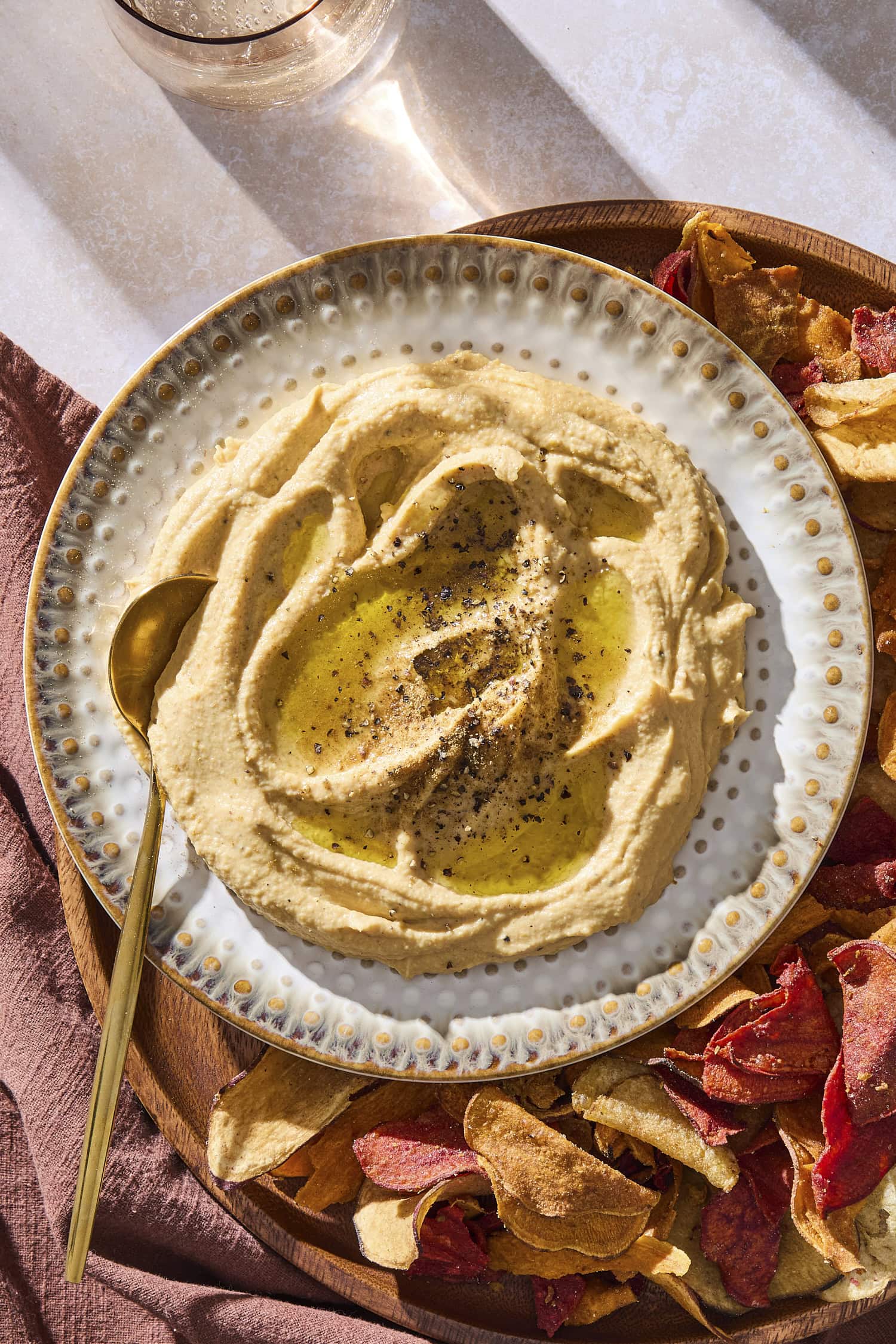 A plate with butternut squash hummus topped with black pepper and a drizzle of olive oil.