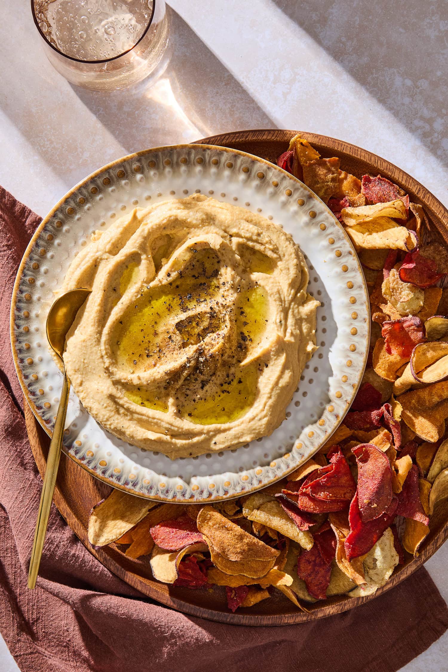 Butternut squash hummus served on a plate on a larger platter with chips.