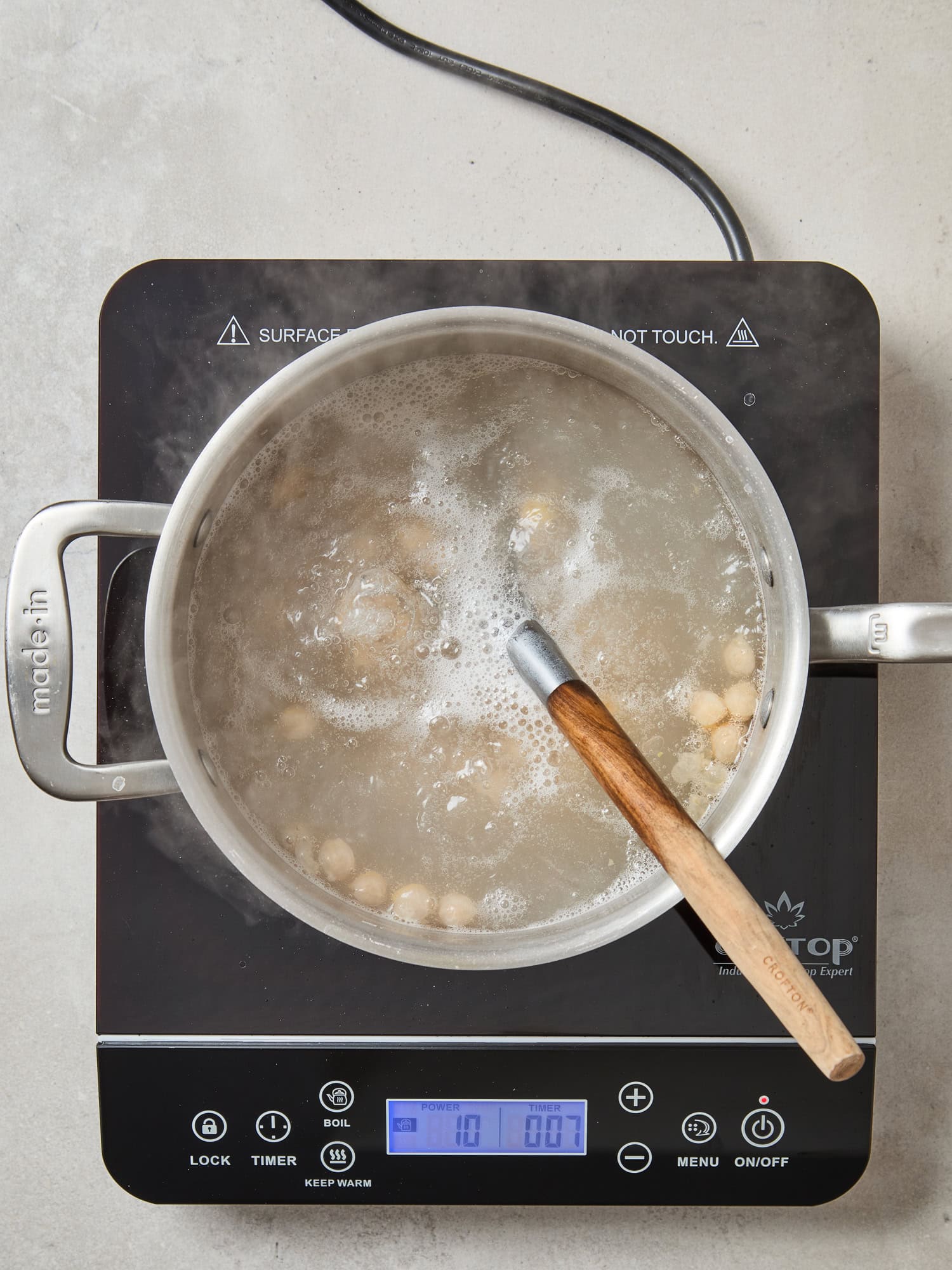 Pot of water boiling with cooking chickpeas.