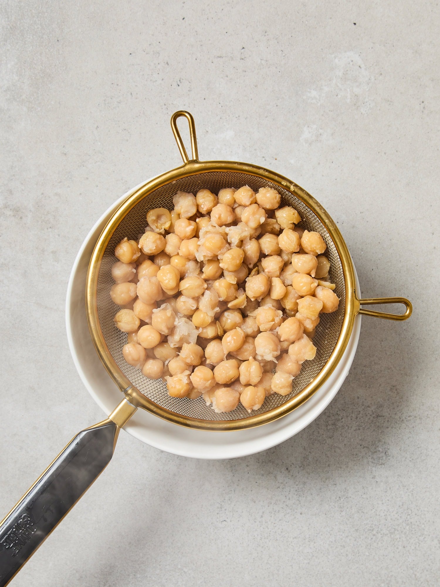 Cooked chickpeas draining in a bowl.