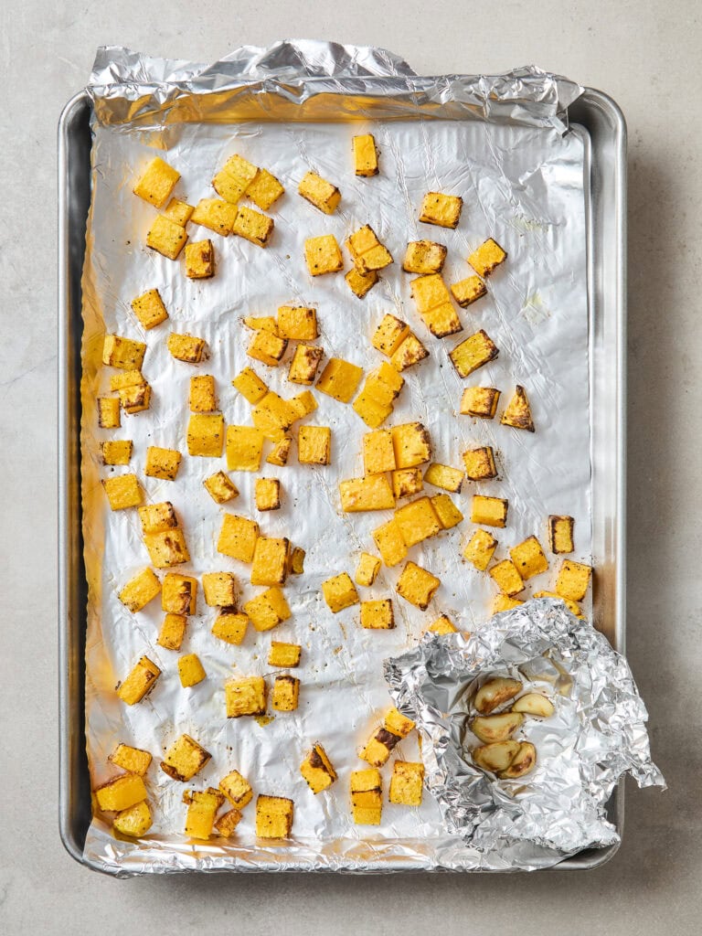 Cubed butternut squash on a baking sheet after being roasted.
